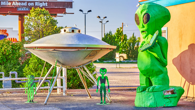 Alien statues next to a silver UFO