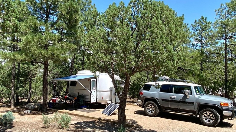An SUV parked with a trailer in a pine forest at Manzano Mountains State Park, New Mexico.