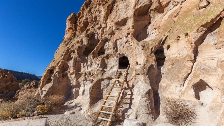Wooden ladder leaning against a cave opening in canyon rock