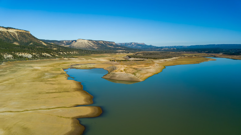 An aerial view of El Vado Lake with mountains in the background underneath a bright blue sky