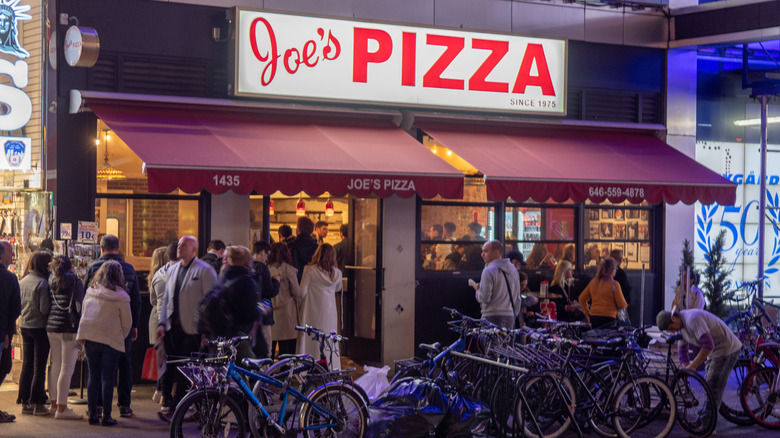 People standing outside of Joe's Pizza on 14th Street in New York City
