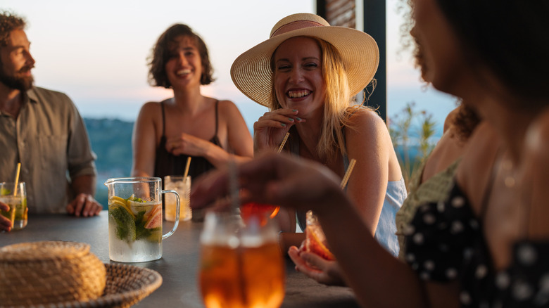 Four friends laughing over glasses of cocktails