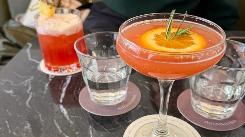 Two colorful cocktails and water glasses on a table in Mockingbird bar