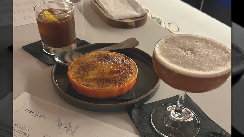 Two cocktails, a desert tarte, and a No More Cafe menu in the foreground