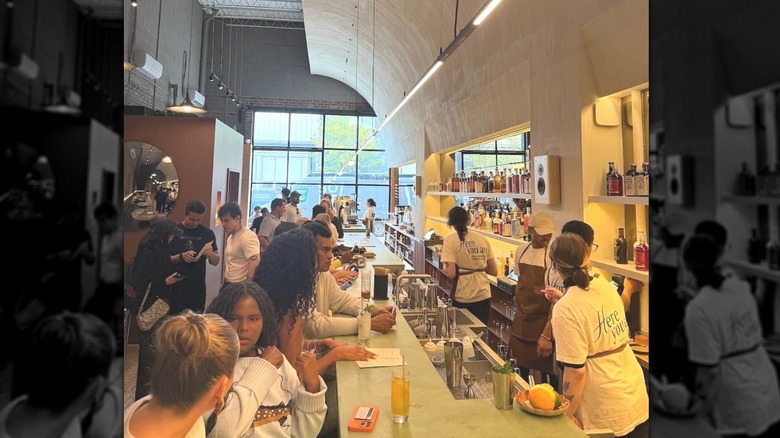 Bartenders behind the bar and crowds on barstools in Soft Bar
