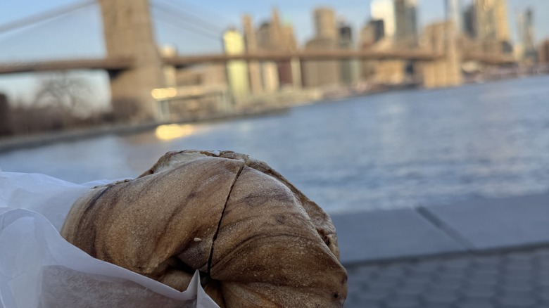Bagel held up with Manhattan skyline in background