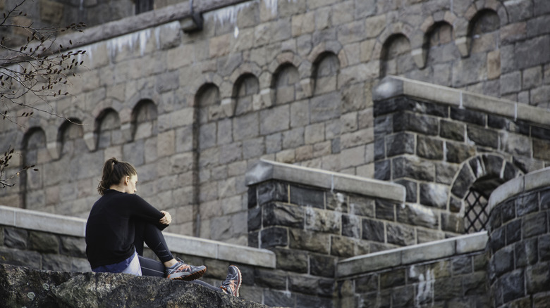 A young woman sits outside the Met Cloisters