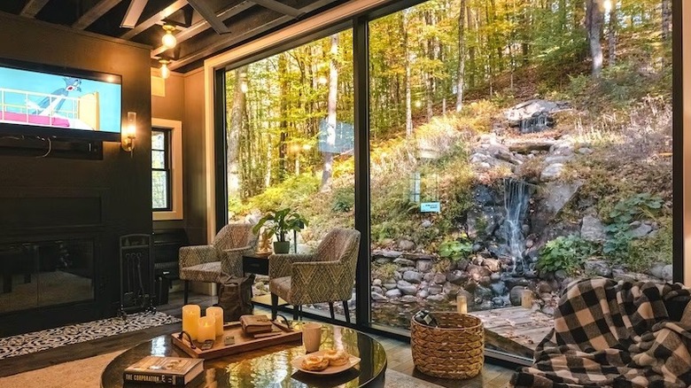 Cozy living room scene looking out window to waterfall and trees