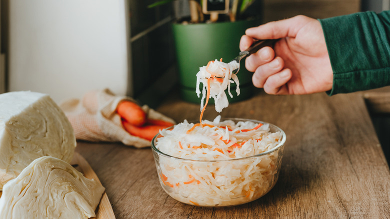 A person eating sauerkraut from a bowl