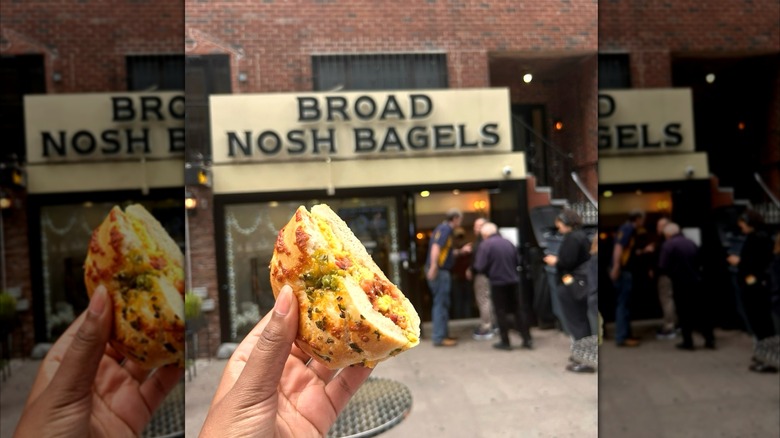 Woman holding  a bagel in front of Broad Nosh Bagels storefront