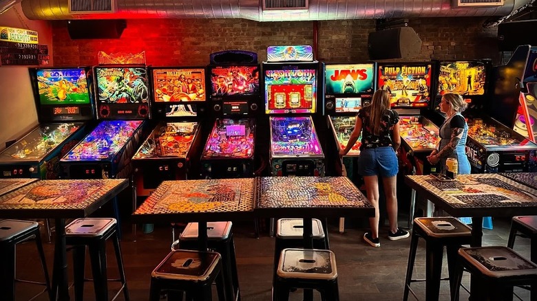 Two women play pinball in the Sunshine Laundromat arcade