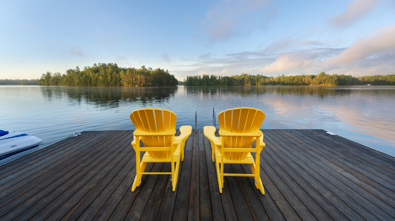 Two Adirondack chairs on a dock facing the lake at dusk