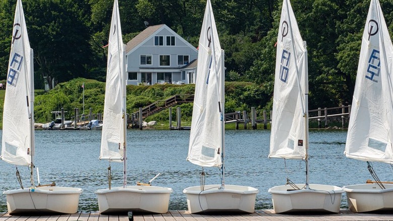 Sailing boats lined up on a dock on Fishers Island with house in the background