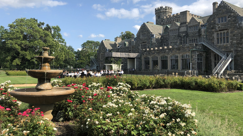 Sands Point Preserve with estate and people in the background, and fountain with flowers in the foreground during the day.