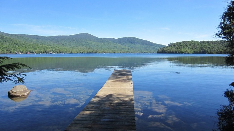 Pier jutting out into serene lake surrounded by pine-forested mountains