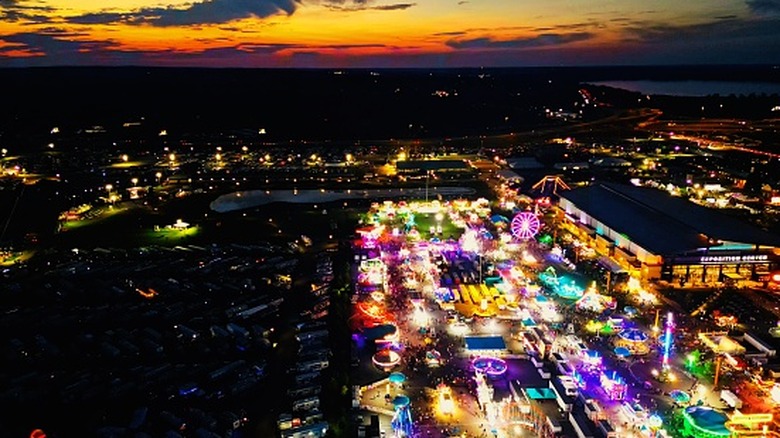 An aerial view of the Great New York State Fair shows the midways brightly lit up against a fading sunset