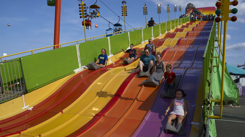 Families slip down a giant slide at the Great New York State Fair on a sunny day