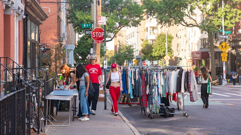 People walking along a street with clothing racks in Williamsburg, Brooklyn, with bridge in background