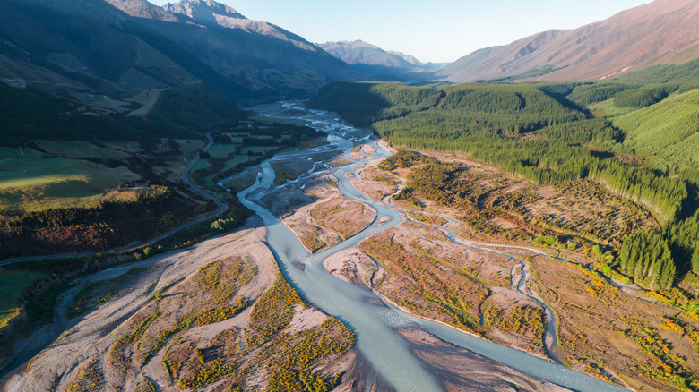 Blue river winding through land and hills, with rugged mountains in the background