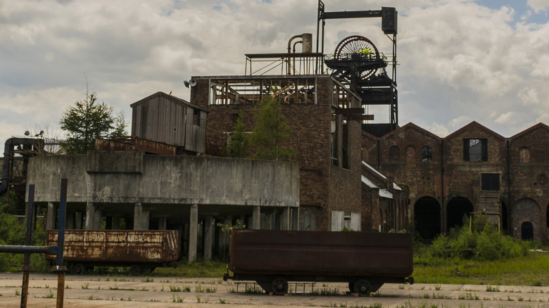 Old brick buildings and structures, with a mine cart in the foreground, at the Newtongrange Mining Museum