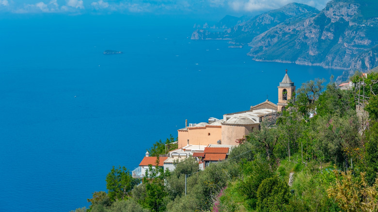 The cliffside church, Chiesa Santa Croce, with pale red walls in front of the blue sea