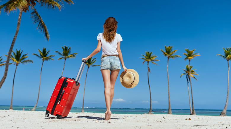 woman with luggage on beach