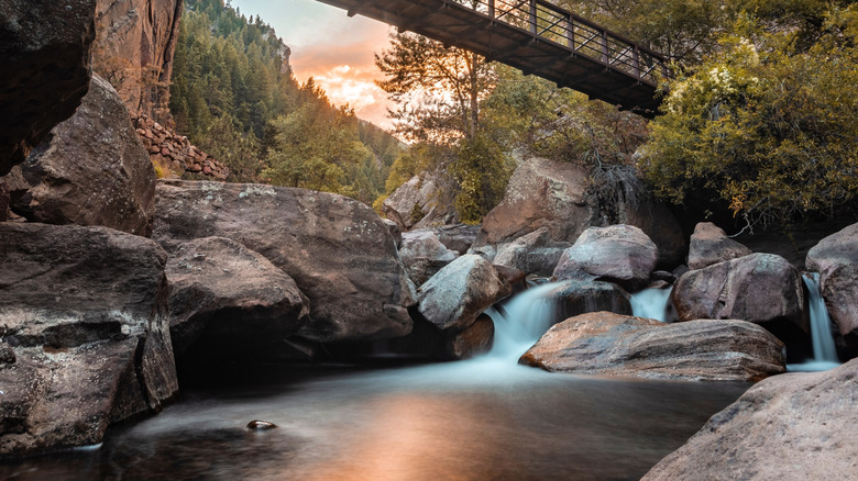 A wood foot-bridge over a waterfall cascading down boulders in Eldorado Canyon State Park