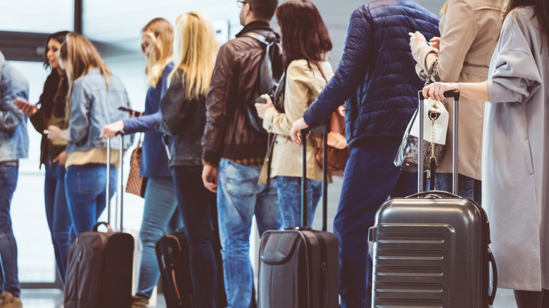 Line of people waiting with suitcases at an airport.