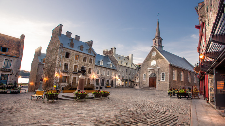 A historic street view of Old Quebec with a church steeple rising above a stone-paved town square.