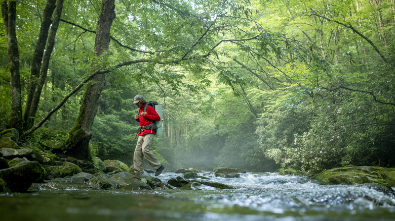 A backpacker crossing a creek in the Great Smoky Mountains National Park in North Carolina