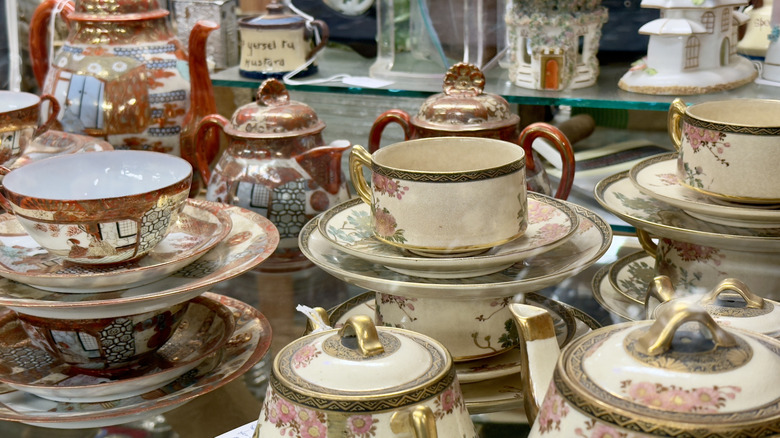 Stacks of porcelain cups and dishes with floral motifs at an antique shop.