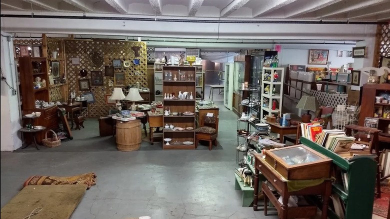 A booth at Lexington Park Antiques with antique lamps, paintings, and furnture.