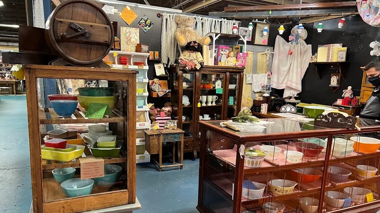 A booth at Sweeten Creek Antiques in Asheville with an antique cupboard filled with glassware.