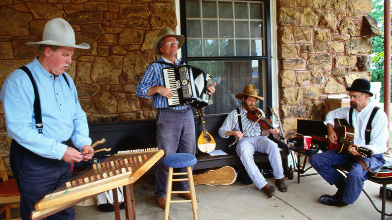 Musicians play traditional instruments in front of a building in an Amish village