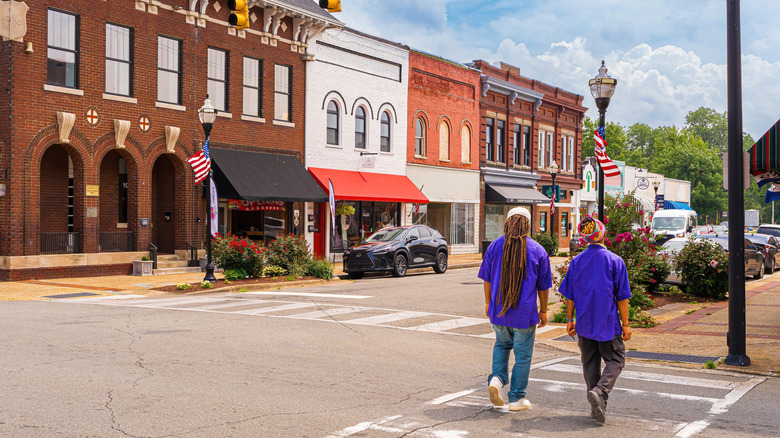Two men cross the road in Downtown Selma near old-school brick buildings and shopfronts.