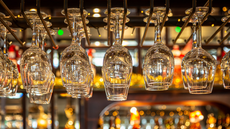 Wine glasses hanging from above a bar