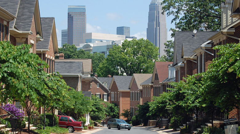 A house-lined street in Dilworth with the skyscrapers of Charlotte in the background