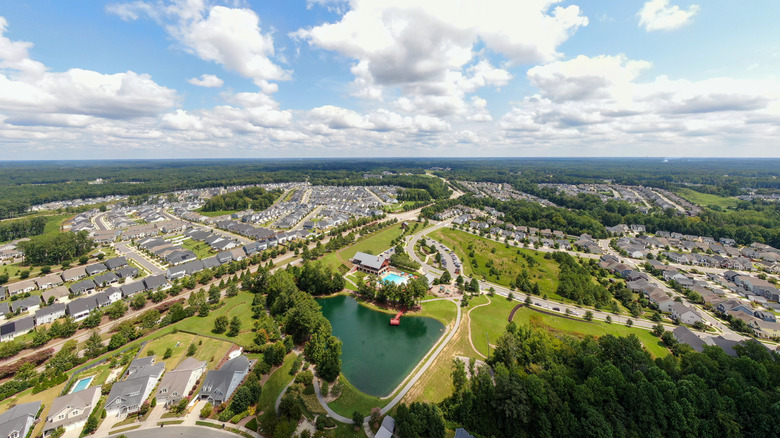 Houses stretch around lake under clouds and blue sky in Wendell, North Carolina