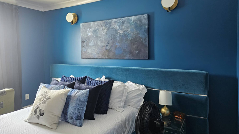 The "Kind of Blue" room at the Magnolia House, with blue walls, blue art, a blue headboard, and white bedding.