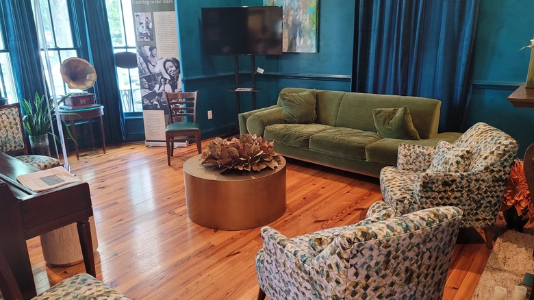 Interior of the Magnolia House living room area with green couch, chairs, and vintage record player.