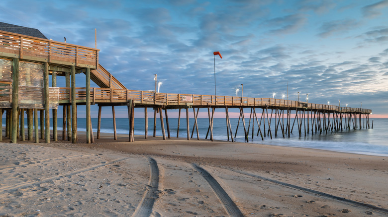The 700-foot-long Avalon Pier stretching out over the ocean with sand and water beneath it.