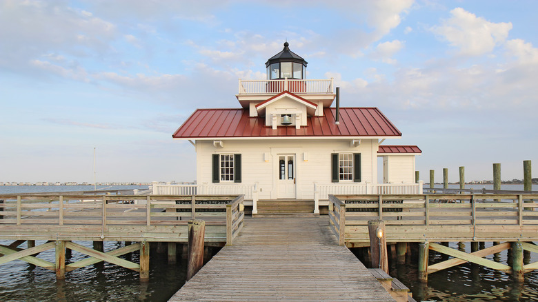 A red and white wooden lighthouse on a pier