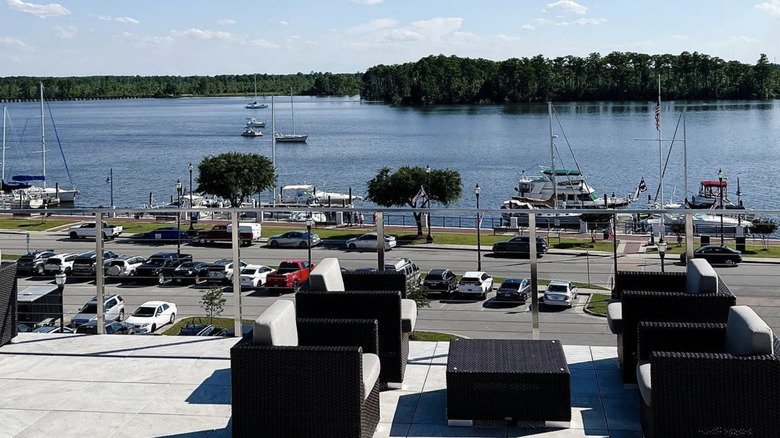 Deck with chairs in front of water with boats anchored.