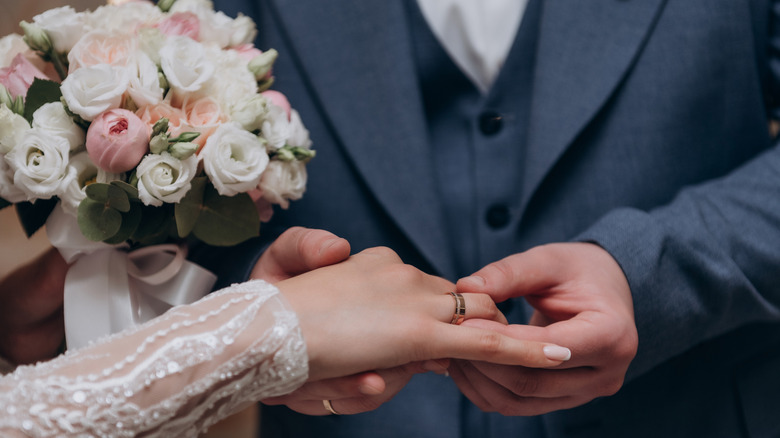 Close up photo of couple's hands and wedding ring during marriage ceremony