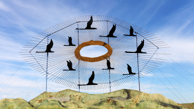 Big metal sculpture of black birds under a blue sky