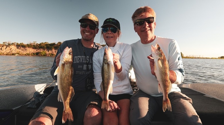 three people on a boat holding fish at Devils Lake, ND