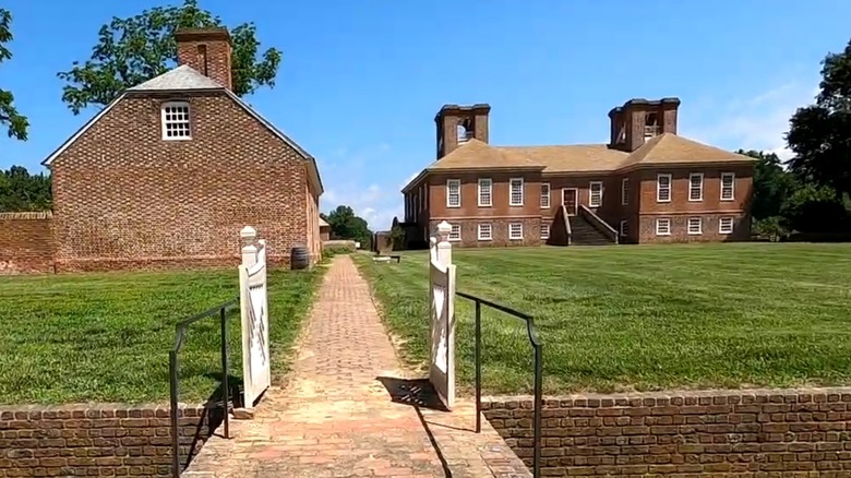 Brick pathway leading to a grassy lawn with two historic buildings at Stratford Hall in Montross, Virginia