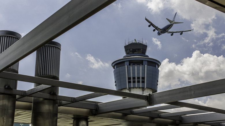 A passenger jet flies over an air traffic control tower at LaGuardia Airport, New York