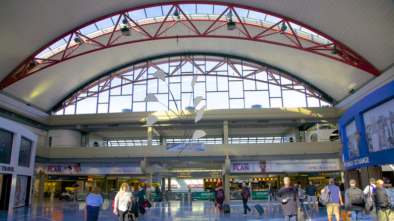 Travelers walking under an arched glass roof in Pittsburgh International Airport