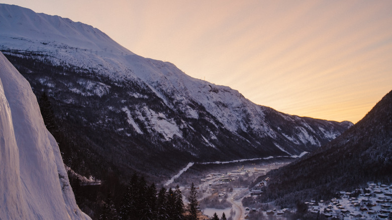 Sunrise in Rjukan, Norway, seen between snowy mountain peaks.